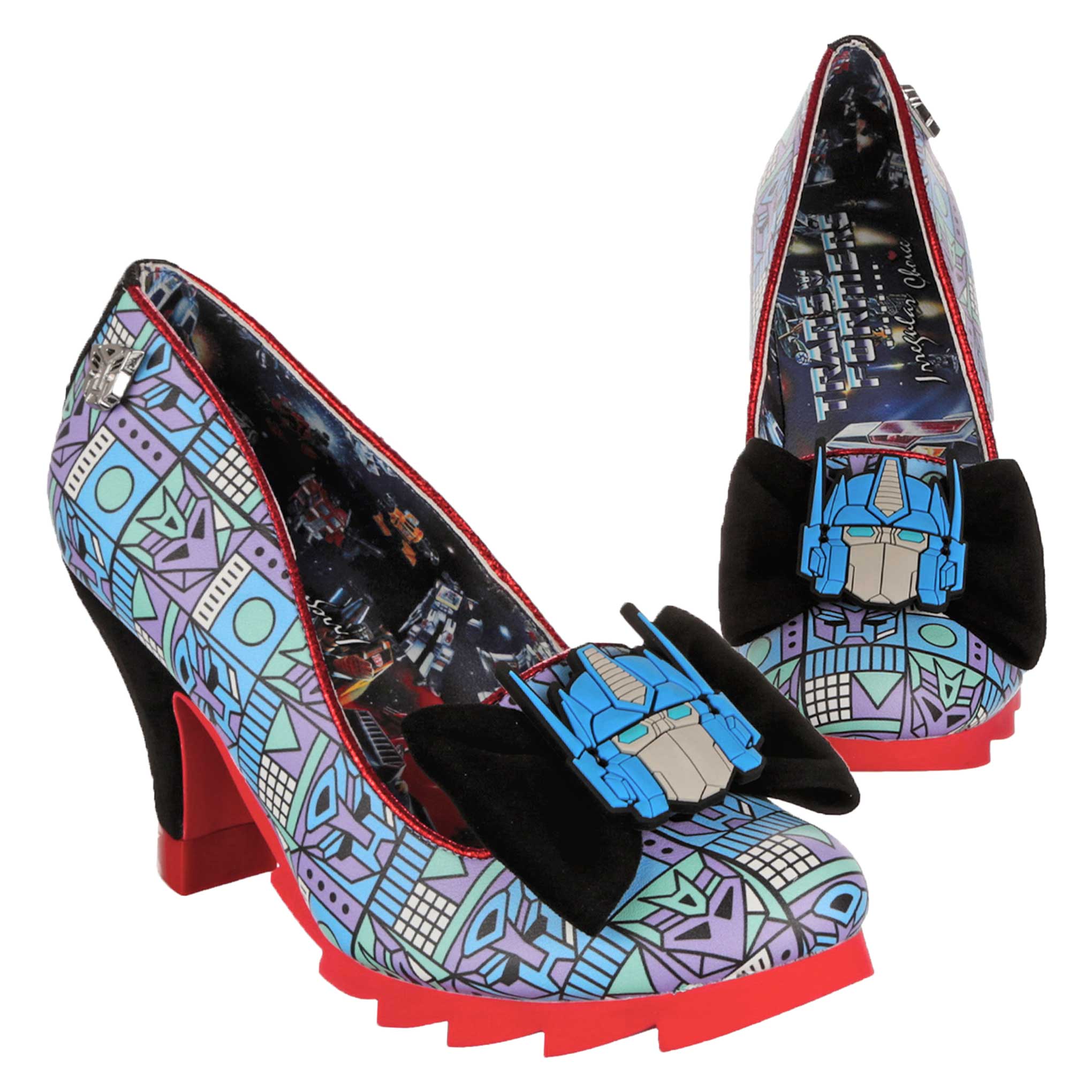 Transformers themed platform high heel shoes featuring a blue and purple geometric pattern with an Optimus Prime decal sitting on a black velveteen bow on the tow of the shoe. Red chunky platform soles contrast with the black velveteen high heel. A blue Transformers print  lines the inside of the shoe showing a classic Transformers battle scene and Transformers X Irregular Choice label. 